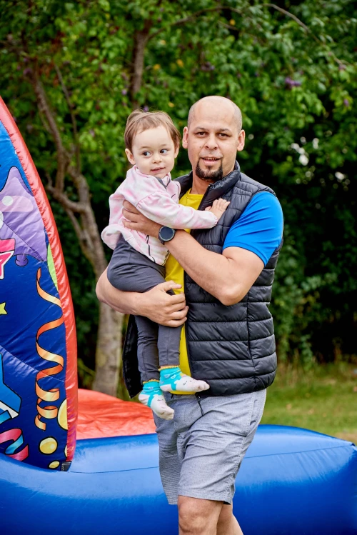 Man holding young girl in arms at play area