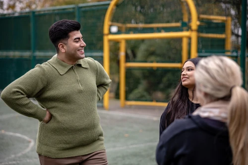 Three teenagers chatting and laughing on a basketball court