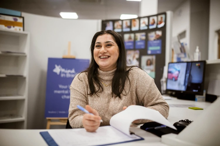Woman sitting at a desk in a reception area welcoming people